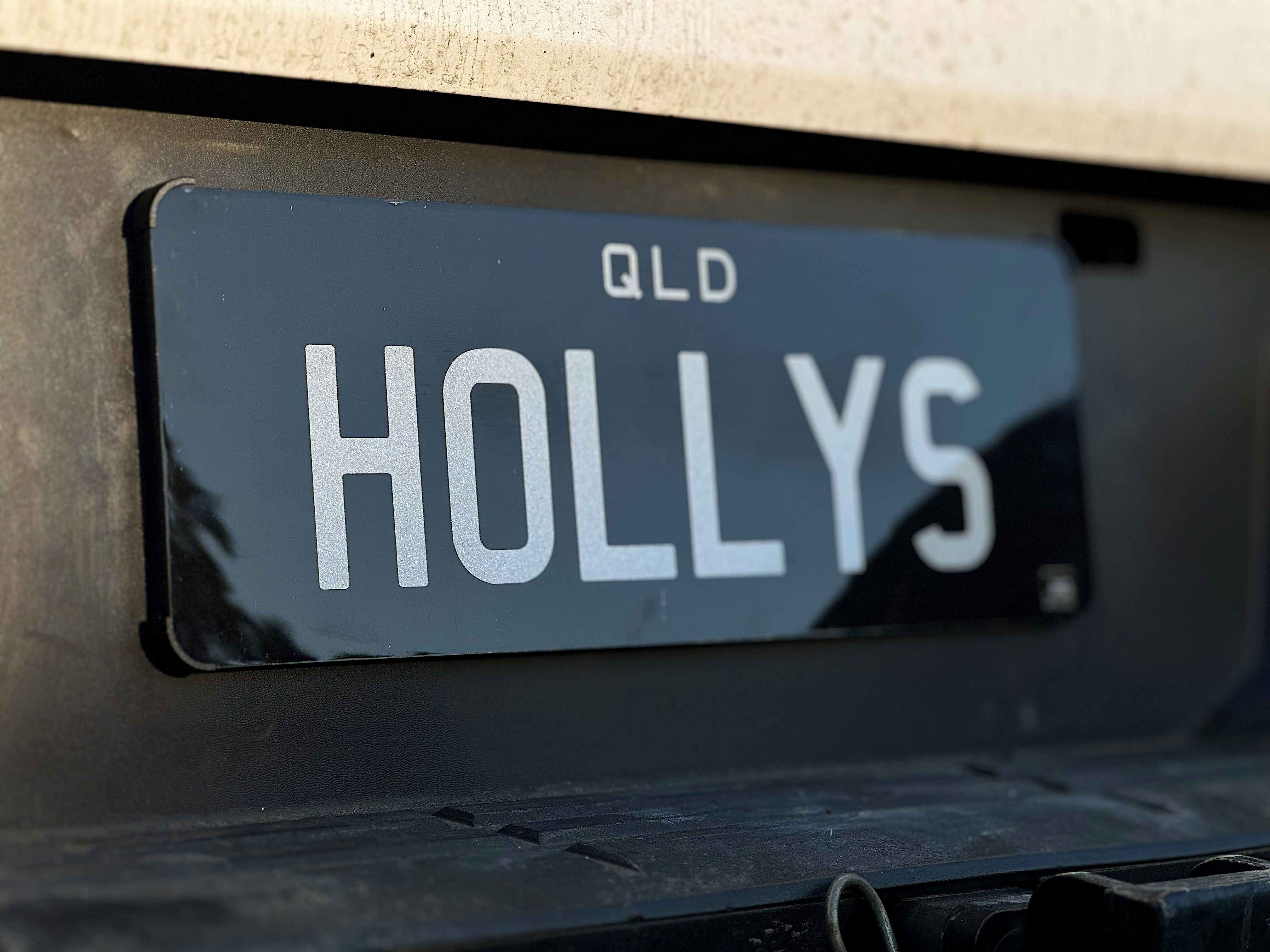 Close-up of Corner Frame Flexi Plate Holder installed on a ute, displaying HOLLYS QLD Prestige Plate.